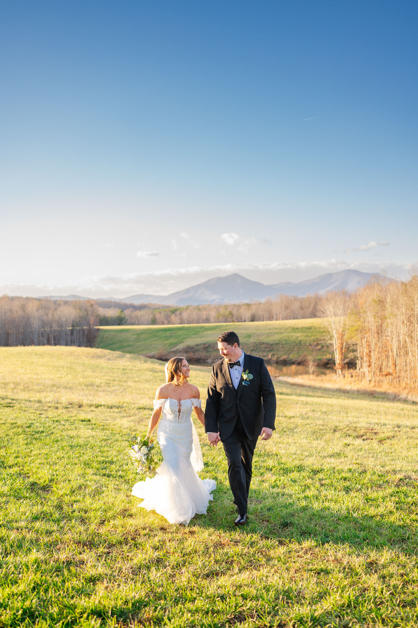 bride and groom walking in front of the mountains at cedar oaks farm